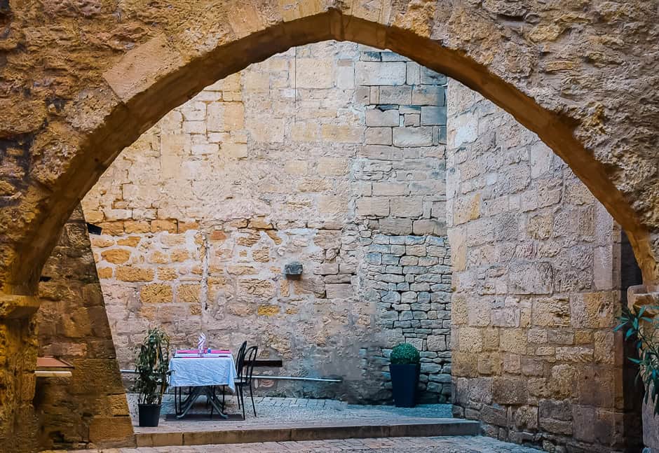 A dining table under a stone arch in Sarlat, France