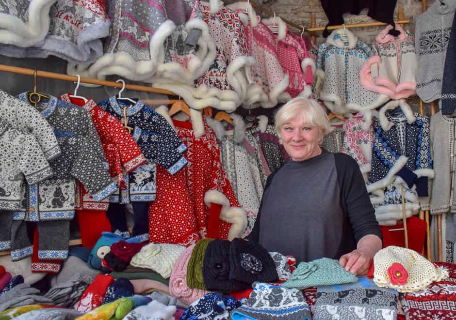 A woman in her Knit Market stall, surrounded by knitted wares