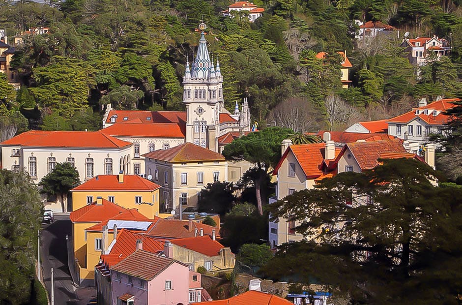 A town with red roofed houses and a fairy tale castle set in a forest in Sintra, Portugal
