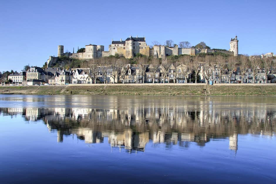 A medieval castle on a bluff reflecting on a river