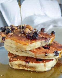 A stck of three thick pancakes with blueberries as syrup drizzles on them at the Muir Hotel on the Halifax waterfront