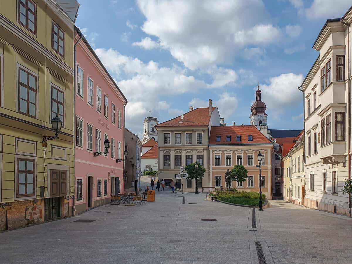 A quaint city square with pastel-coloured buildings in Gyor, Hungary.