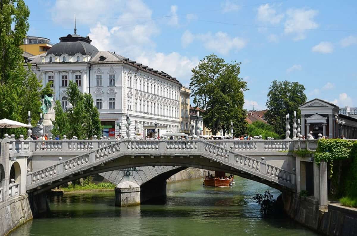 A bridge over a river with a white building in the background in Ljubljana, Slovenia.