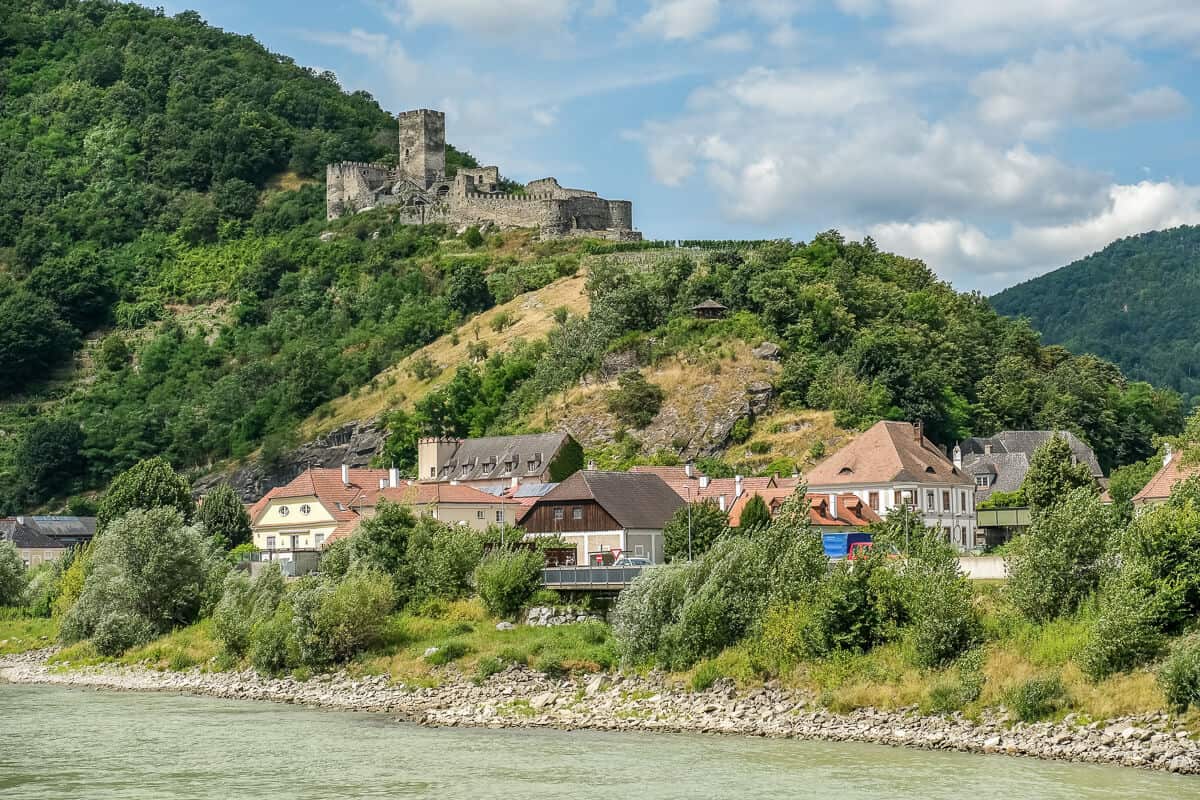 A castle on a hill and a village beside the Danube River in the Wachau Valley in Austria