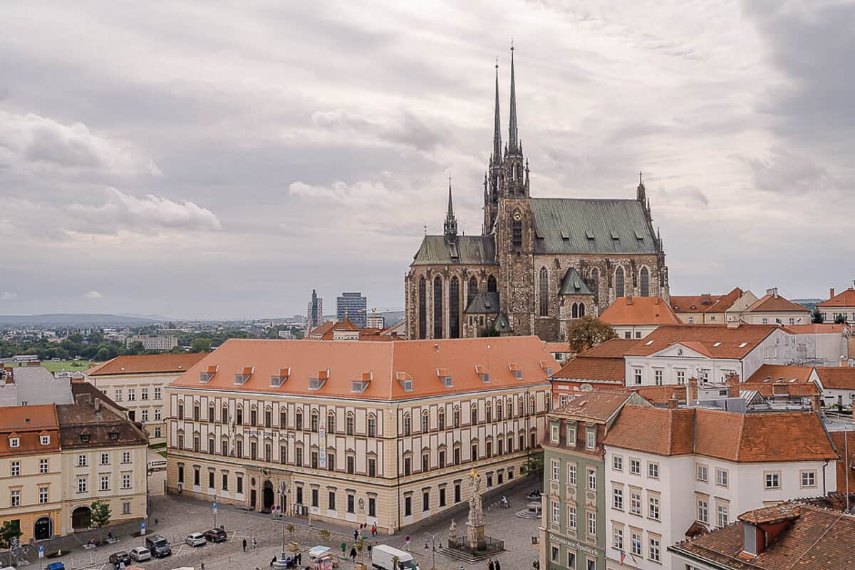 A large gothic cathedral stands above a red roof buildings in Brno, Czech Republic