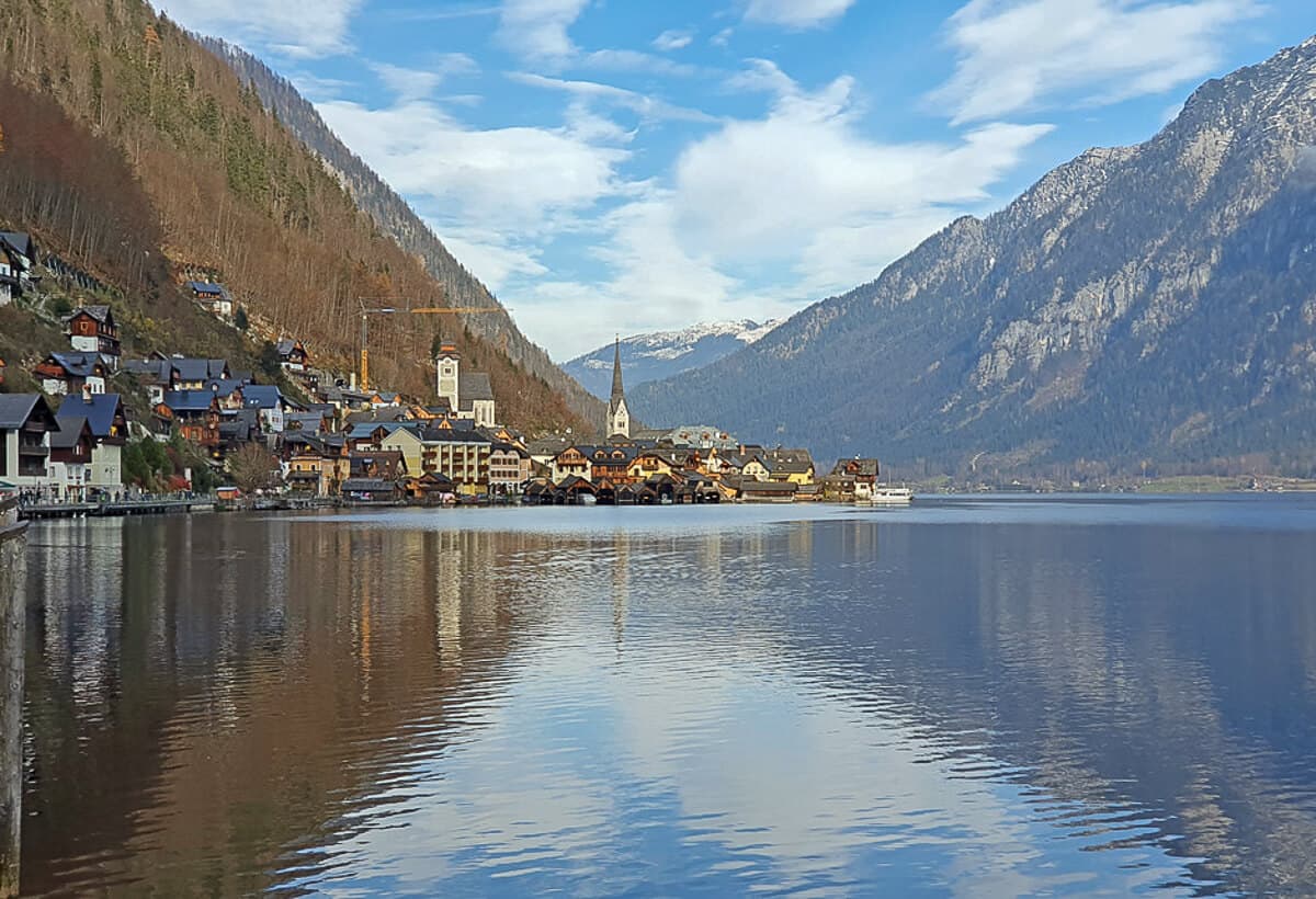 The quaint village of Halstatt with church spires sits on a lake nestled in the Austrian Alps