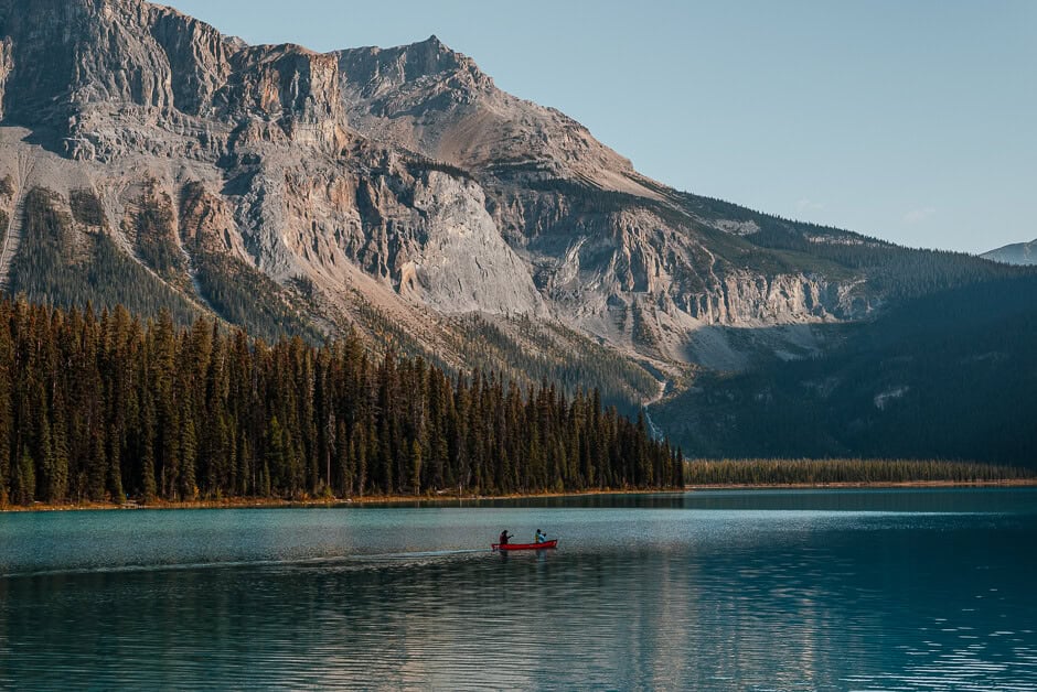 A couple in a canoe on a lake with a mountain backdrop - - one of the best things to do in Yoho National Park in Canada.